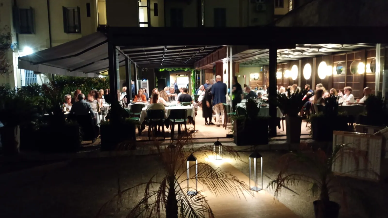 Lo stesso dehor di sera, illuminato e con i tavoli pieni